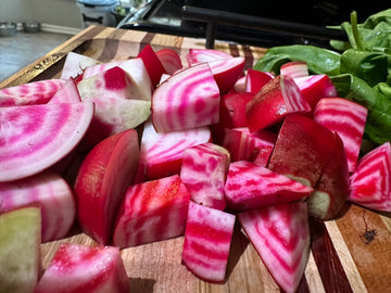 pink and white striped beets cut up on a board