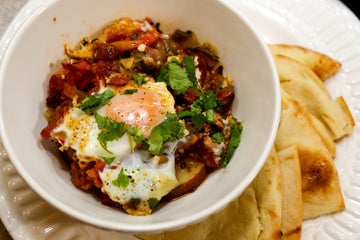 Egg over tomato and potatoes with fresh green clintro