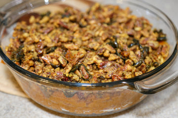 Sweet potatoes in a glass bowl with candied pecans and candied jalapeno topping