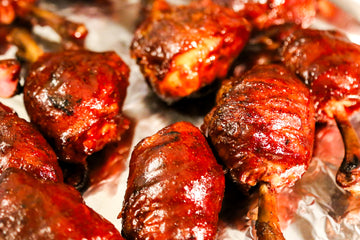 BBQ chicken leg pops on a plate with baked potato and slaw. 